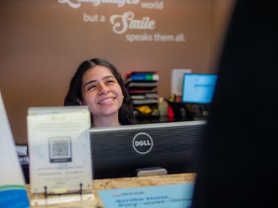 a bright, smiling face greeting patients at Elite Dental
